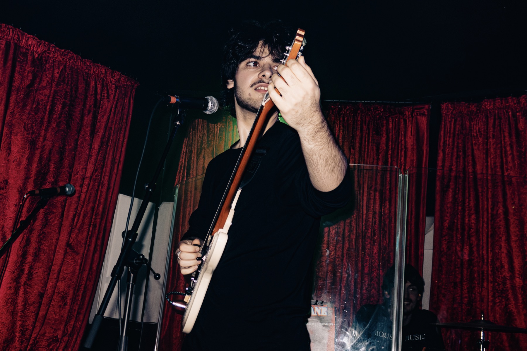 Zoning Out guitarist performing in front of red curtains